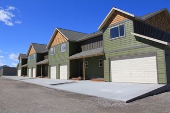 A row of green houses with white garage doors